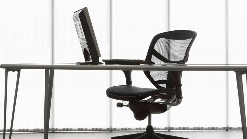 Still life shot of computer monitor and keyboard with office chair.